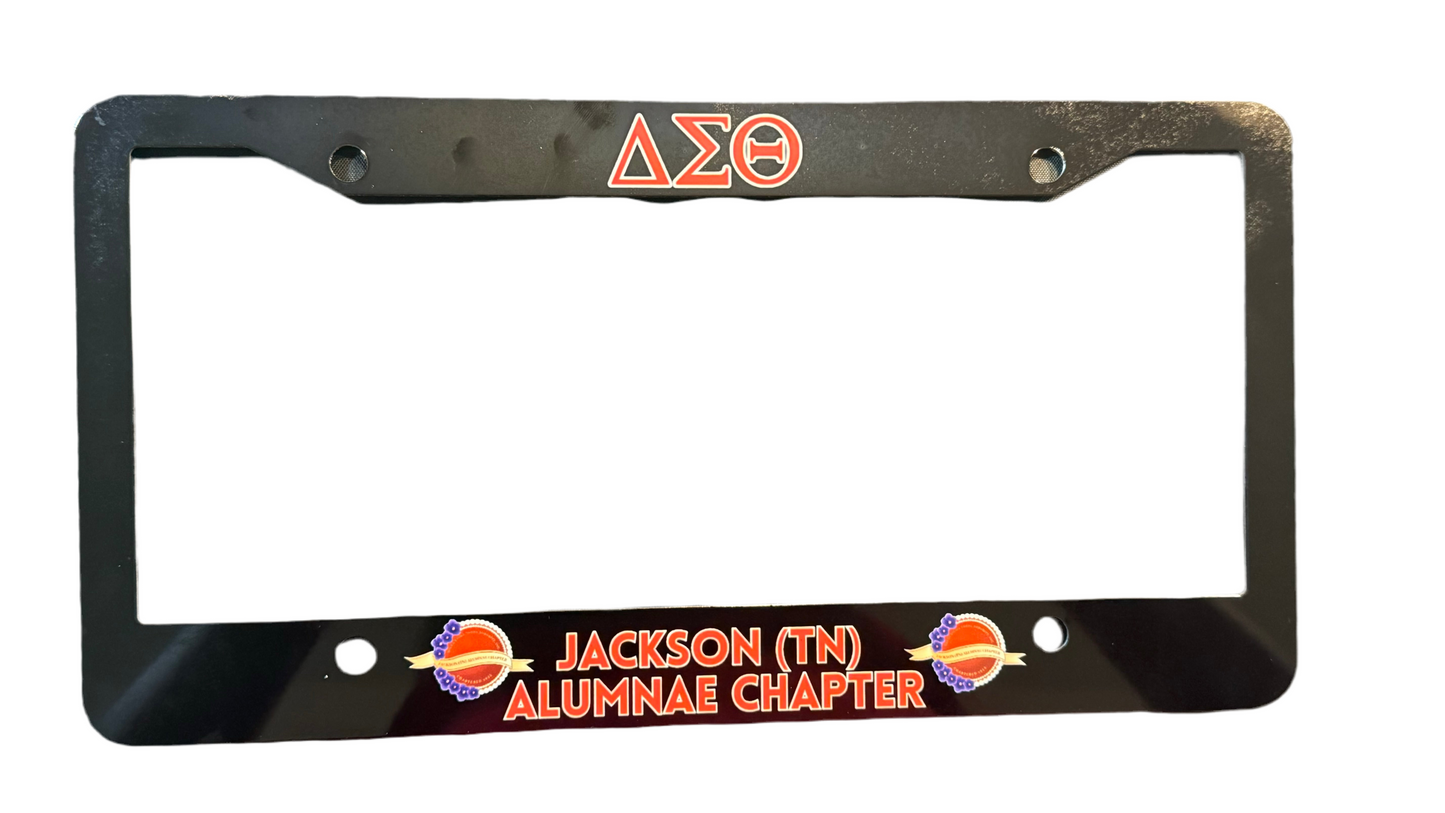 Black license plate frame with red text and Greek letters