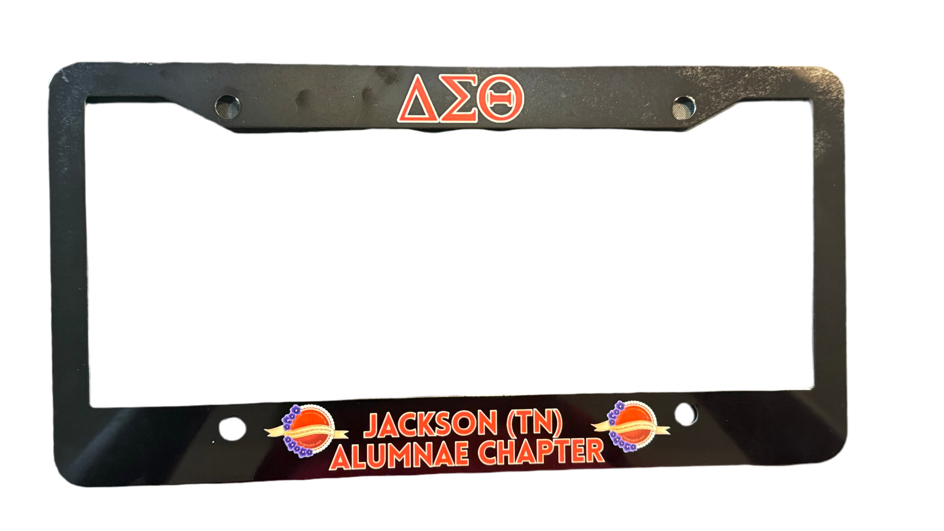 Black license plate frame with red text and Greek letters 